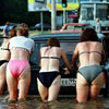 several babes in bikinis push a flooded car