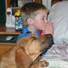 young boy and his dog are praying together